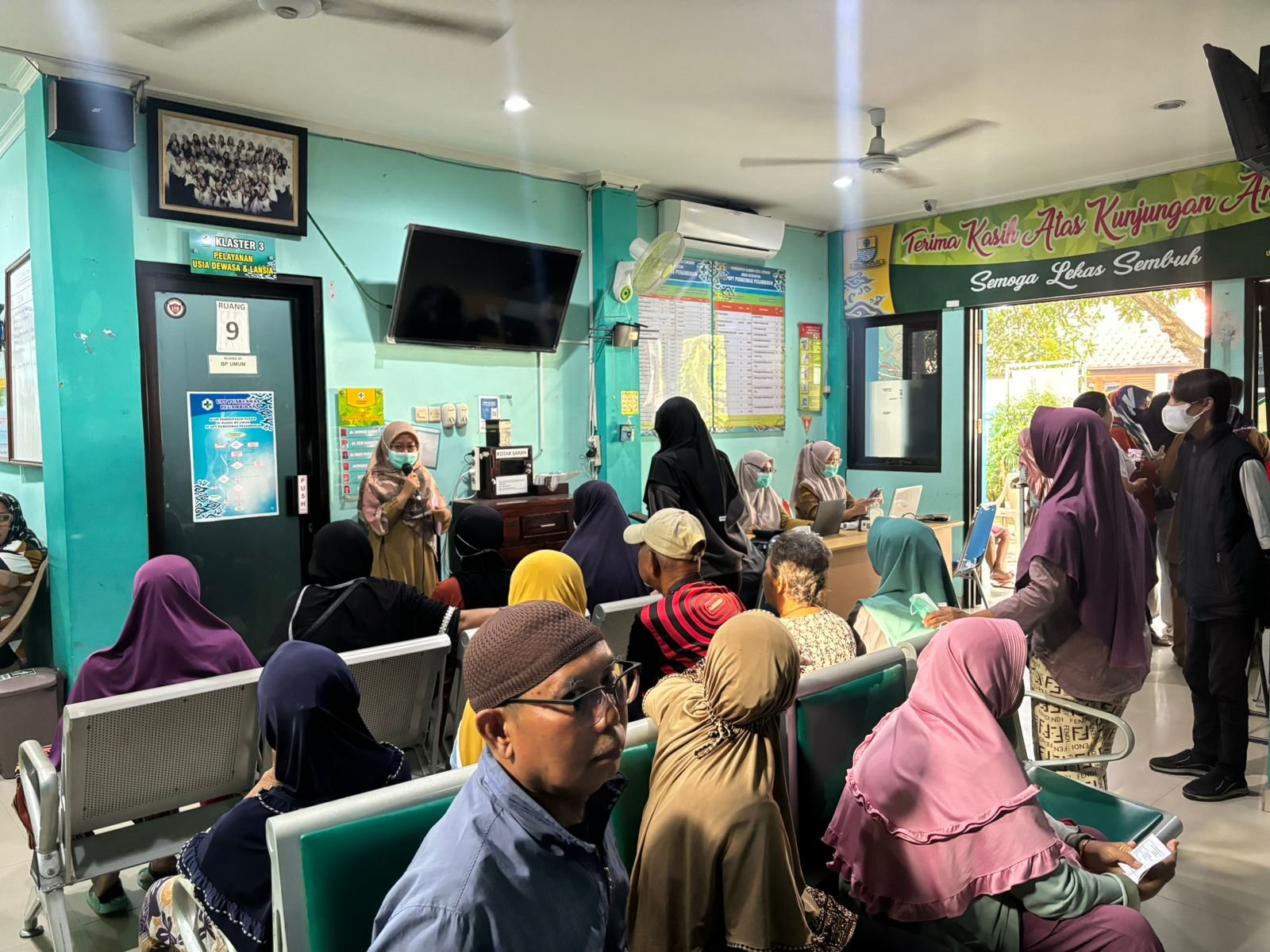 KEGIATAN PENYULUHAN DALAM GEDUNG TENTANG HFMD ATAU FLU SINGAPURA KEPADA PENGUNJUNG PUSKESMAS DI RUANG TUNGGU OLEH PETUGAS SURVEILANS PUSKESMAS PEGAMBIRAN